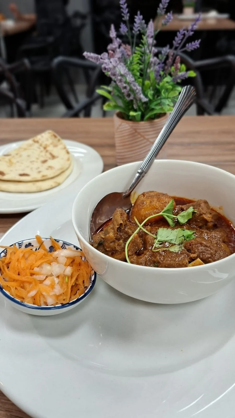 Curry dish served with roti and sides at NewTown Brew